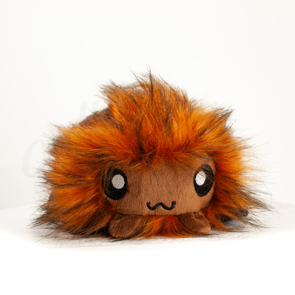 Front view of a cuttlepod plush toy, showcasing its unique form with large, cartoonish eyes, ruffled fins, and a cuddly, furry texture.