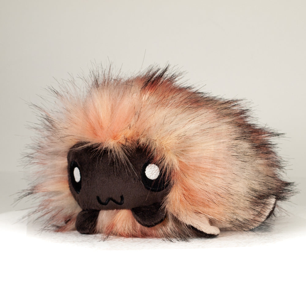 Front view of a cuttlepod plush toy, captured at a slight angle to highlight its charming features: large, cartoonish eyes, ruffled fins, and a cuddly, furry texture.