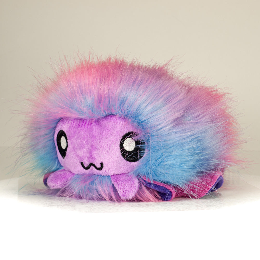 Front view of a cuttlepod plush toy, captured at a slight angle to highlight its charming features: large, cartoonish eyes, ruffled fins, and a cuddly, furry texture.